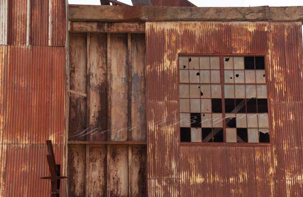 Rusted abandoned metal building with windows broken out.  Mine building