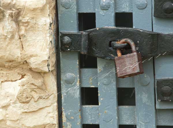 Locked, rusty padlock on a metal door