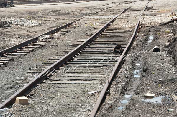 Rundown abandoned railroad tracks in need of repair with trash glass bottles bricks