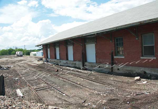 Abandoned brick railroad depot with railroad tracks