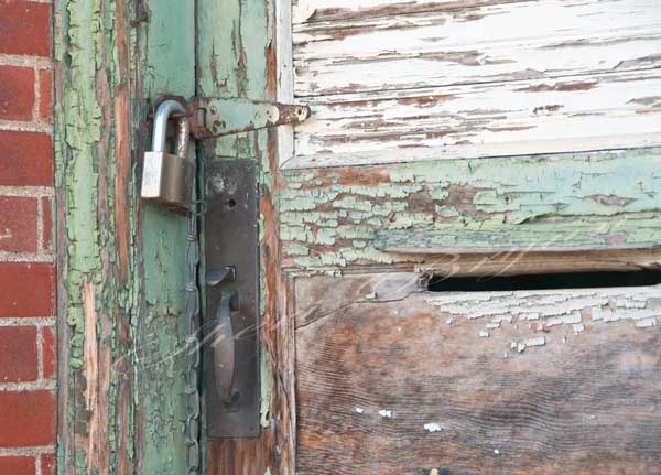 Wooden door on an abandoned building with peeling paint and a padlock and a mail slot