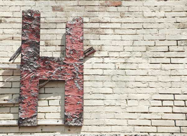 Wooden, red letter H on a brick wall