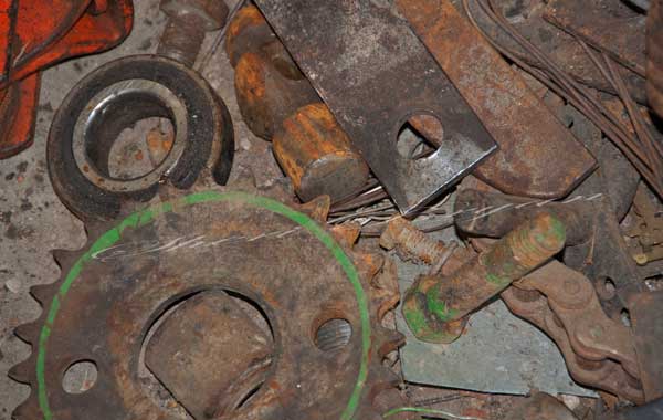 Discarded rusty gears bolts bearings and a hammer head