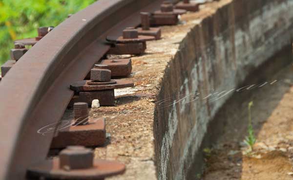 Curved mine rail track with large rusted bolts