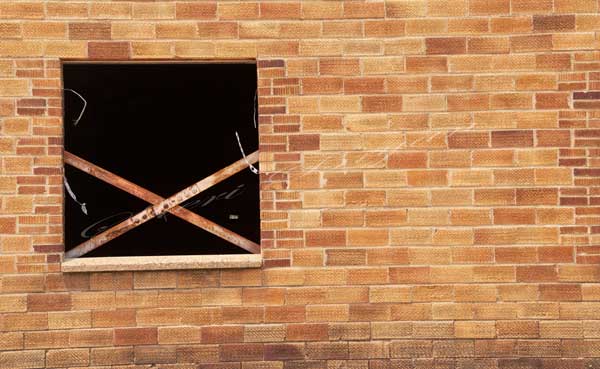 Broken out window in an abandoned brick building.  Letter X